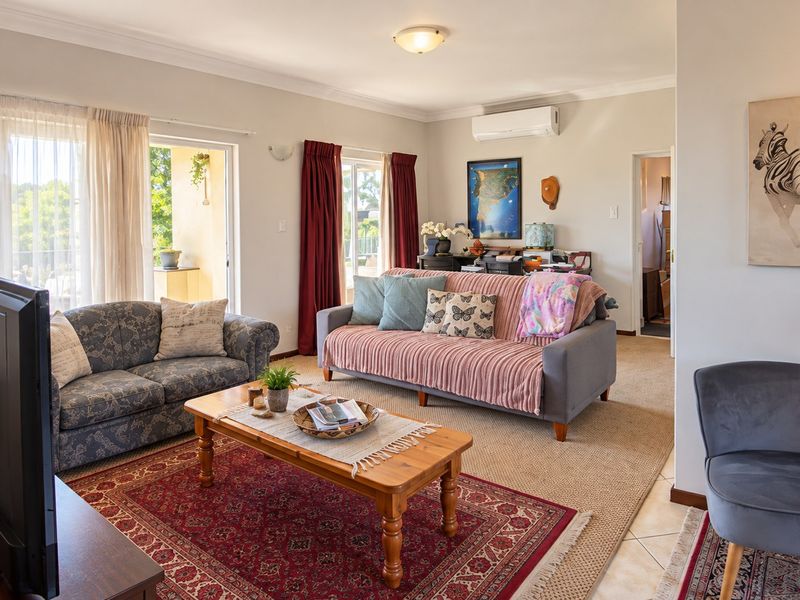 Spacious living room featuring neutral walls, carpeted flooring, a wall-mounted air conditioning unit, and sliding glass doors providing access to an outdoor area.
