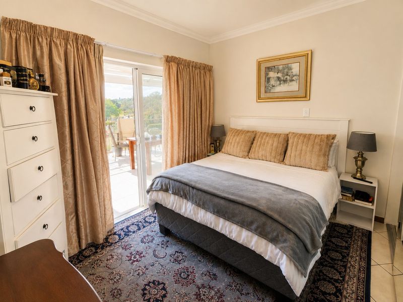 A well-maintained bedroom featuring tiled flooring, built-in cupboards, and a sliding glass door providing direct access to an outdoor patio area.