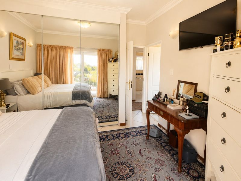 A well-maintained bedroom featuring mirrored sliding wardrobes, crown molding, tiled flooring, and direct access to a private balcony.