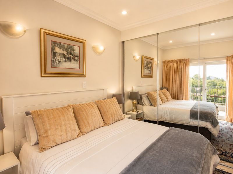 A well-maintained bedroom featuring mirrored sliding wardrobes, recessed lighting, and direct access to a private balcony through sliding glass doors.