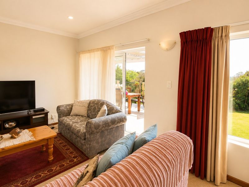 A bright living room featuring large windows and a sliding glass door that provides direct access to an outdoor patio area.