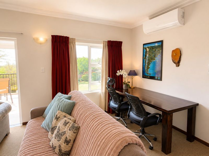 A functional home office space featuring a split-system air conditioner, neutral carpeting, and direct access to an outdoor balcony through a sliding glass door.
