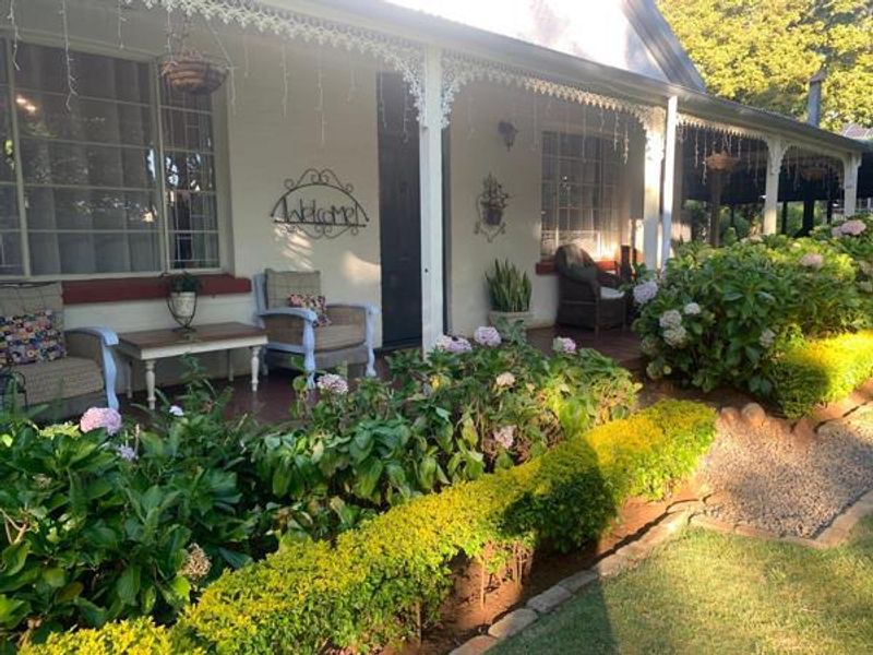 A charming covered veranda featuring decorative ironwork, tiled flooring, and direct access to the front garden area.