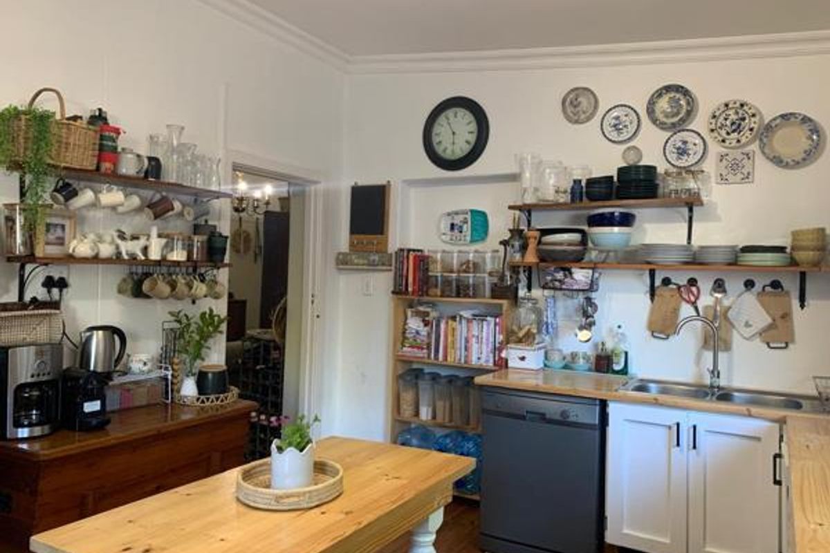 A functional kitchen featuring wooden countertops, open shelving, a double bowl sink with mixer tap, and an integrated dishwasher.