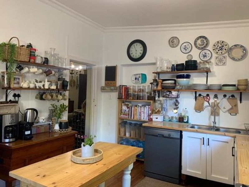 A functional kitchen featuring wooden countertops, open shelving, a double bowl sink with mixer tap, and an integrated dishwasher.
