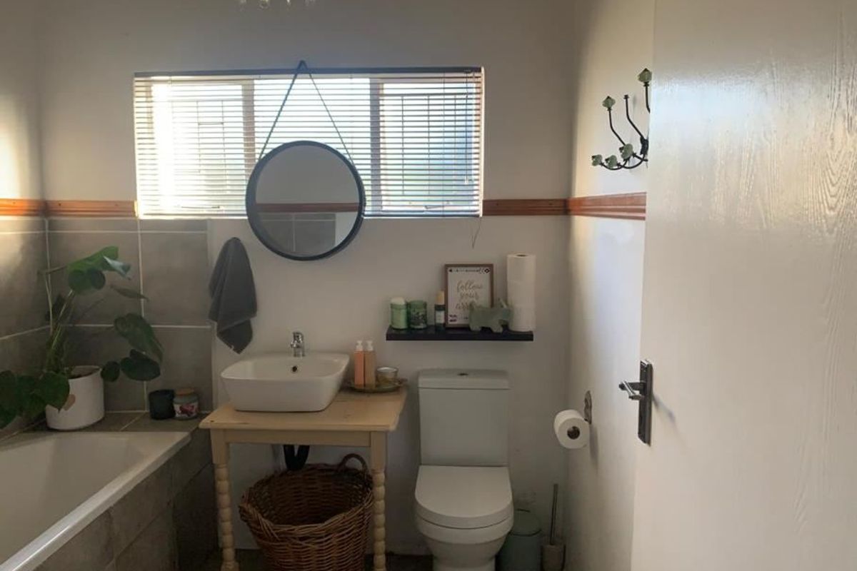 A functional bathroom featuring a built-in bathtub, tiled wall accents, a modern vessel sink, and a standard toilet with natural light from the window.