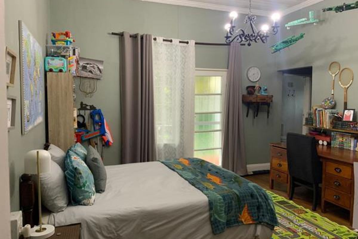 A well-maintained bedroom featuring crown molding, a classic chandelier, and a glass-paneled door providing natural light and access to the exterior.