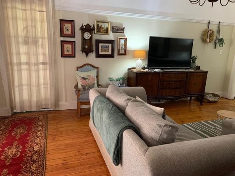 A cozy living room featuring warm hardwood flooring, classic picture rails, and a glass-paneled door providing natural light.