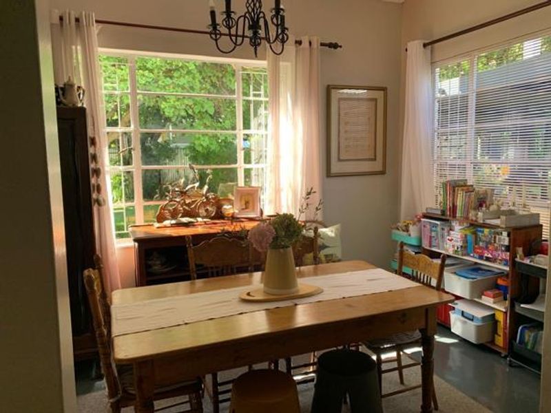 A bright dining room featuring large windows that provide ample natural light and views of the garden.