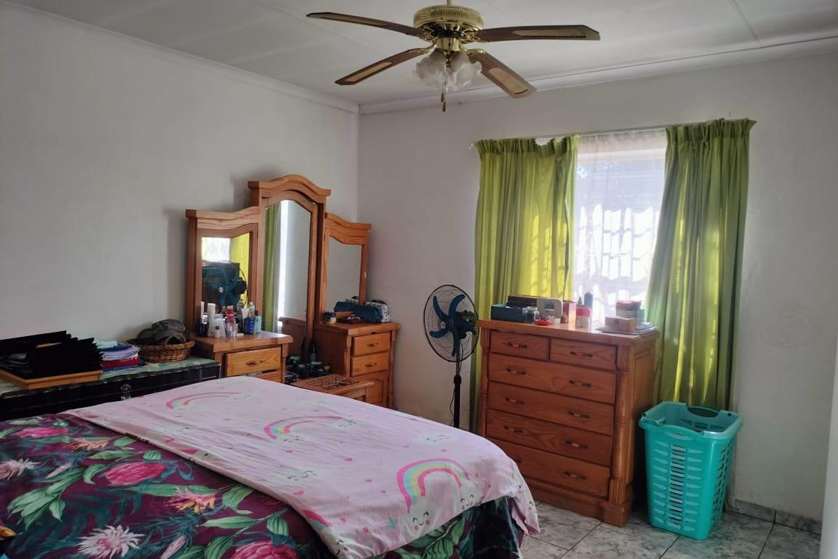 A standard bedroom featuring tiled flooring and a ceiling fan, offering a functional space with natural light from the window.