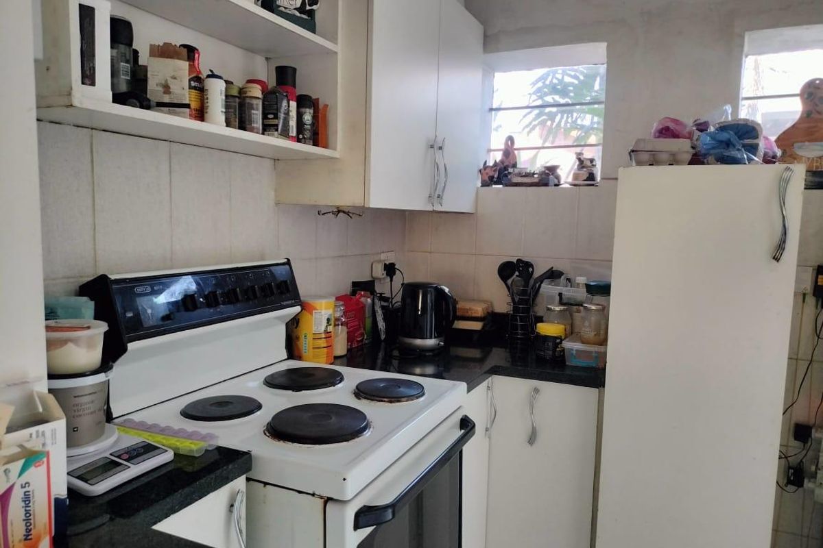Compact kitchen featuring built-in cabinetry, granite countertops, tiled backsplash, and a freestanding electric stove with oven.