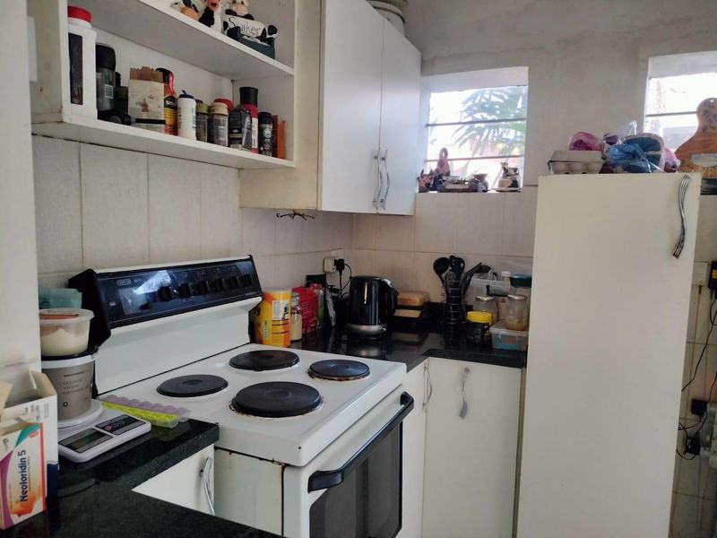 Compact kitchen featuring built-in cabinetry, granite countertops, tiled backsplash, and a freestanding electric stove with oven.