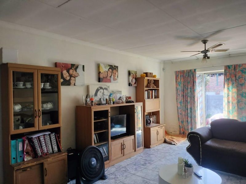 A living room featuring tiled flooring, a ceiling fan, and a sliding glass door leading to the exterior.