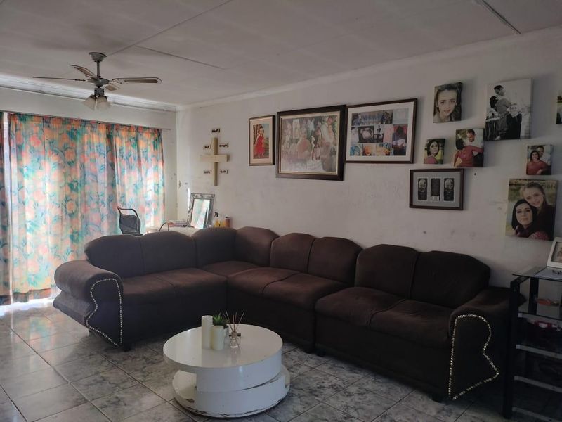 A living room featuring tiled flooring, a ceiling fan, and a sliding glass door providing access to the exterior.