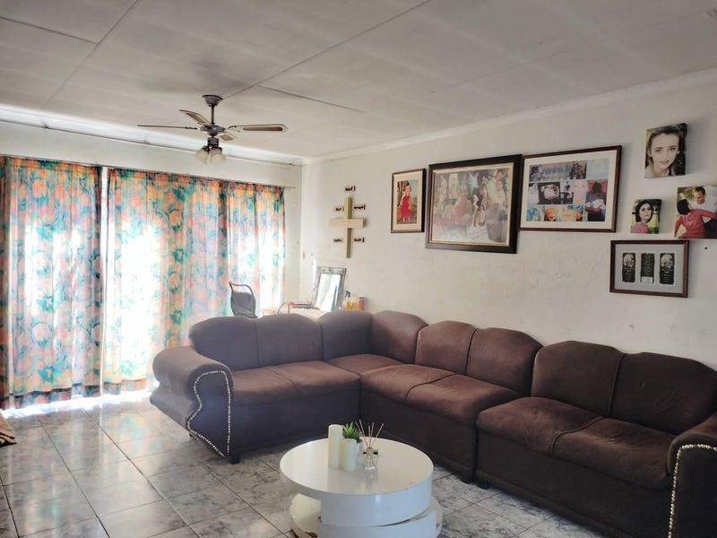 A living room featuring tiled flooring, a ceiling fan, and a large sliding glass door providing natural light.