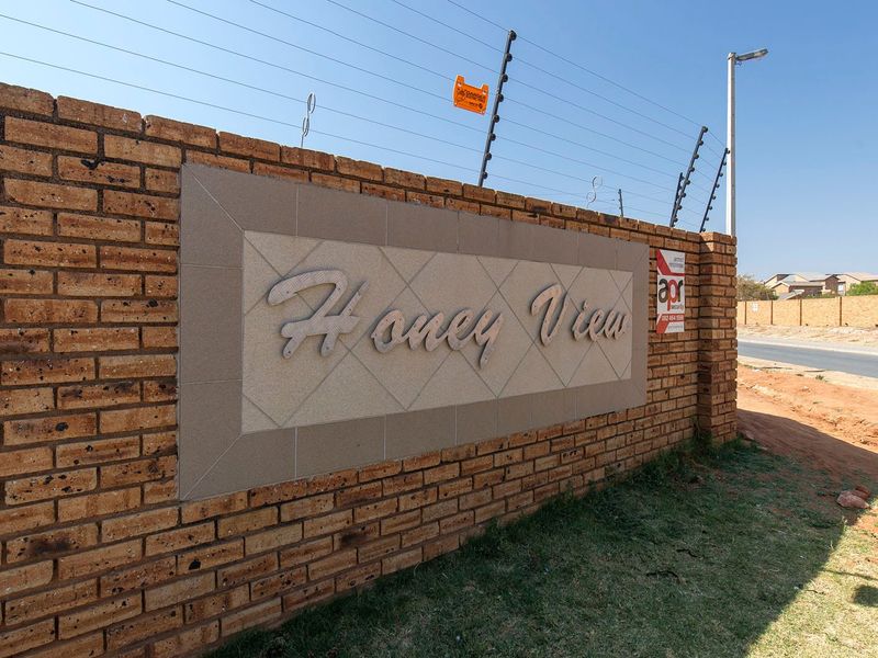 Exterior view of the Honey View complex entrance featuring a face brick boundary wall with integrated electric security fencing.