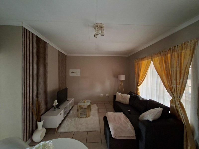 A living room featuring tiled flooring and decorative vertical wall paneling, providing a neutral base for interior design.