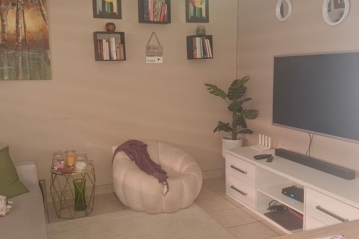 A cozy living room area featuring tiled flooring and a wall-mounted television setup, providing a comfortable space for relaxation.