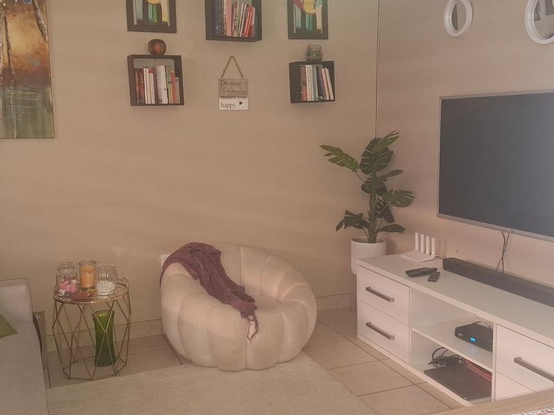 A cozy living room area featuring tiled flooring and a wall-mounted television setup, providing a comfortable space for relaxation.