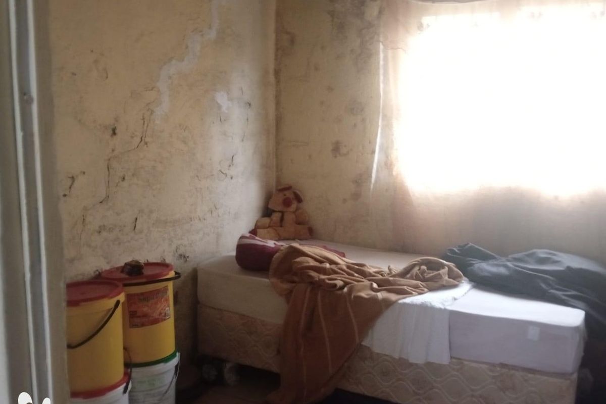 A bedroom space requiring significant wall repairs and refurbishment to address visible surface damage and staining.