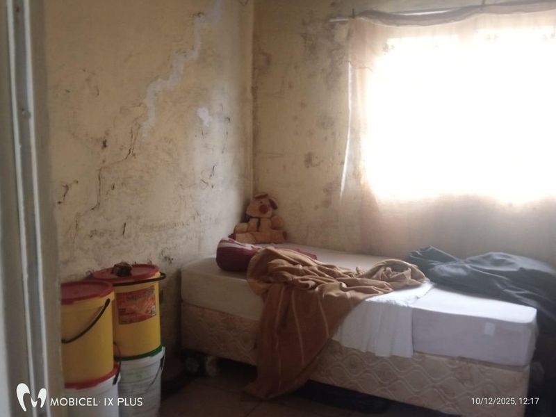 A bedroom space requiring significant wall repairs and refurbishment to address visible surface damage and staining.