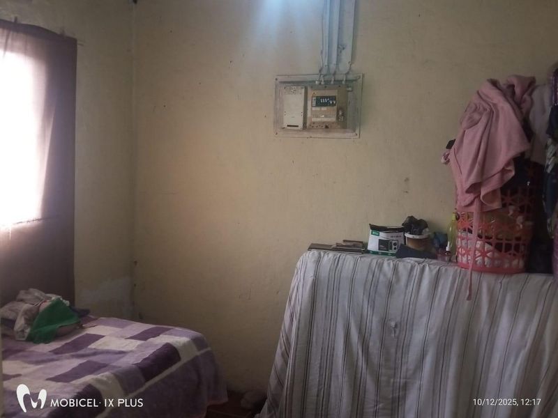 A bedroom featuring a wall-mounted electrical distribution board, showing signs of wear and requiring cosmetic maintenance to the wall surfaces.