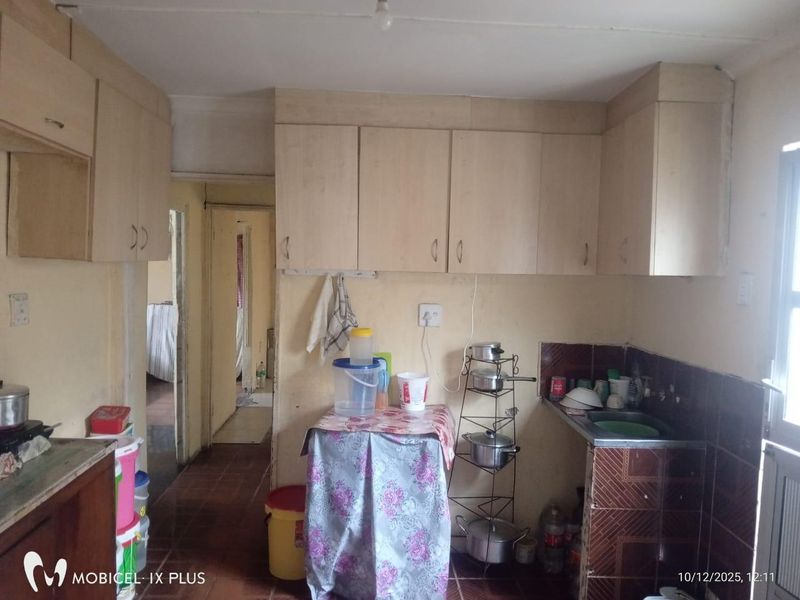 A functional kitchen space featuring built-in cabinetry, a tiled splashback, and a sink, offering potential for modernization and cosmetic updates.