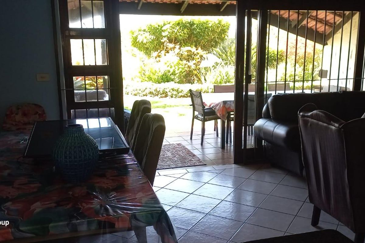 Living area featuring tiled flooring and large sliding glass doors providing direct access to an outdoor patio and garden space.