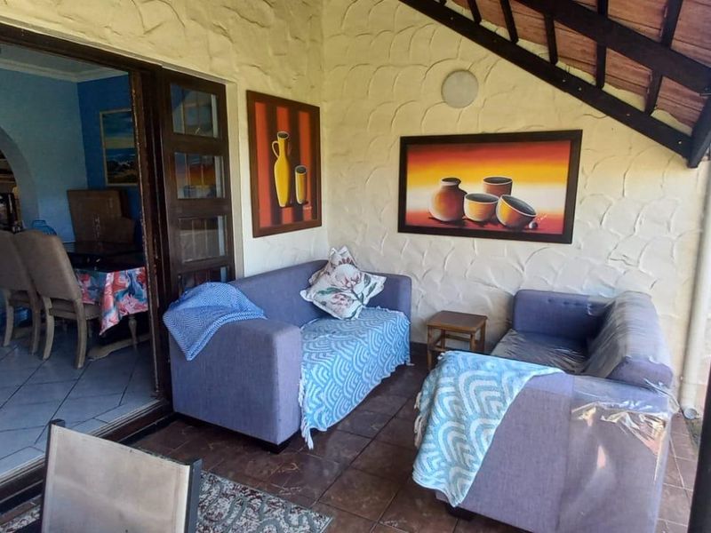 Covered patio area with tiled flooring and exposed timber rafters, providing seamless access to the interior living space through sliding glass doors.