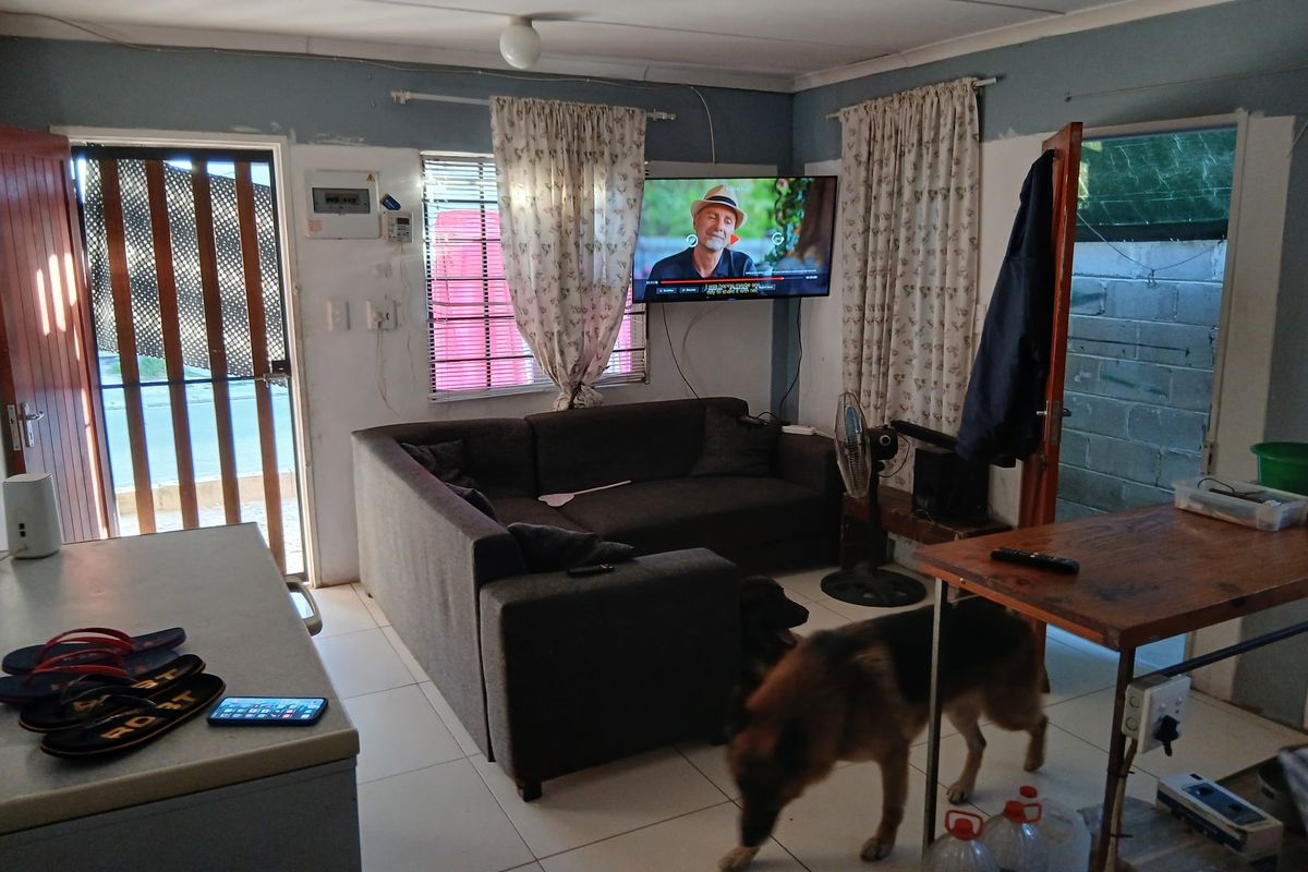 Living room area featuring tiled flooring and wall-mounted television, requiring cosmetic updates to wall finishes and electrical cable management.