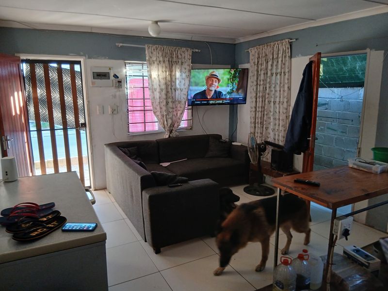 Living room area featuring tiled flooring and wall-mounted television, requiring cosmetic updates to wall finishes and electrical cable management.
