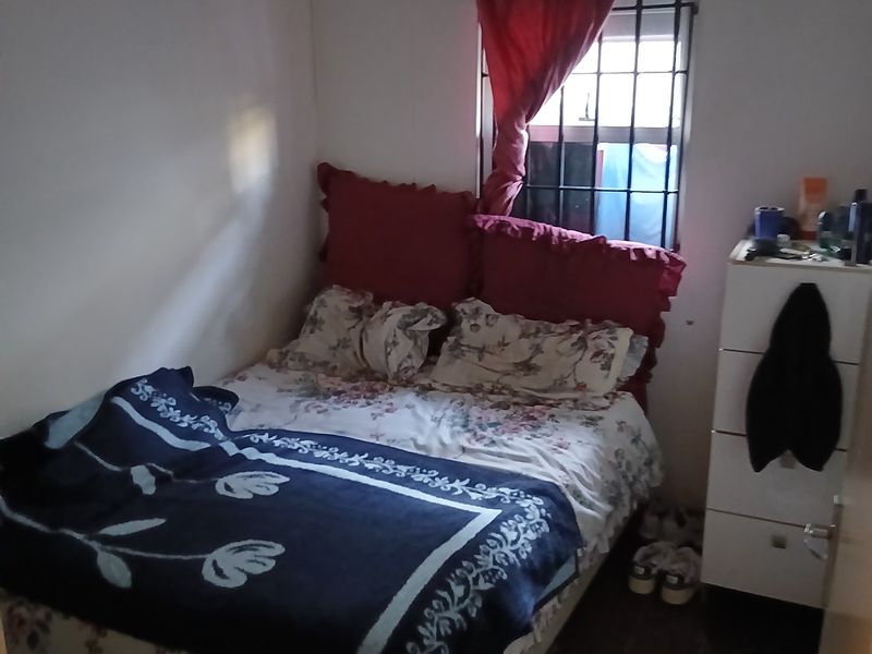 A compact bedroom featuring tiled flooring and a window fitted with security bars.