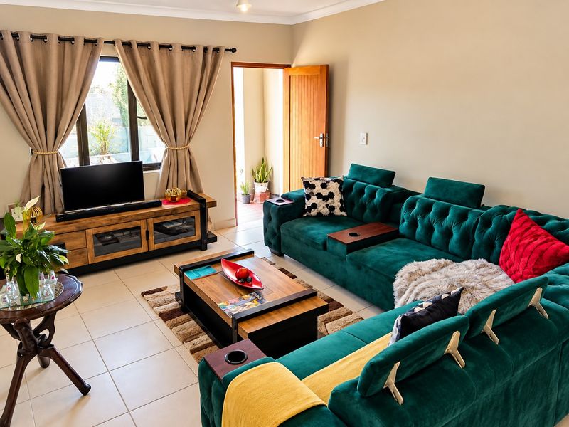 A well-maintained living room featuring neutral wall tones, tiled flooring, and direct access to an outdoor area through a timber door.