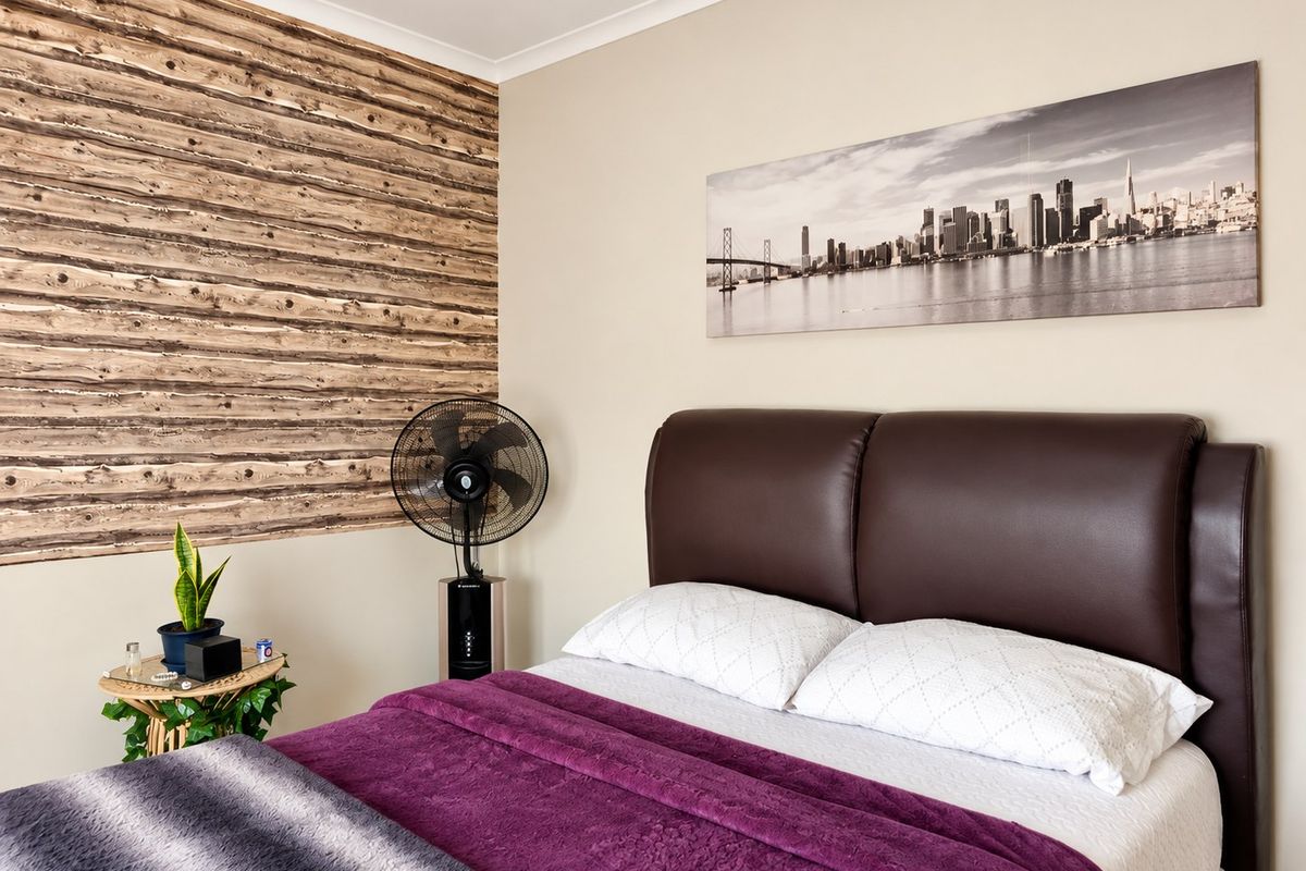 A well-maintained bedroom featuring a decorative wood-look accent wall and neutral paint finishes.