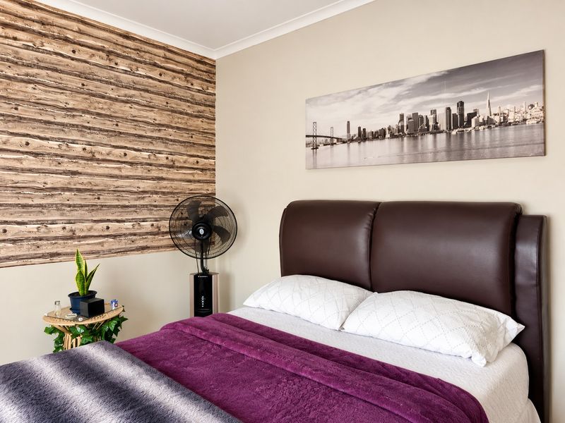 A well-maintained bedroom featuring a decorative wood-look accent wall and neutral paint finishes.