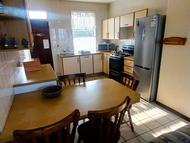 Open plan kitchen and dining area featuring tiled flooring, laminate cabinetry, and a functional layout with a tiled splashback.