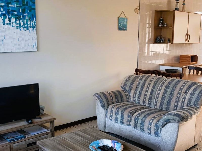 Open-plan living and dining area featuring tiled flooring and a functional kitchen space with built-in cabinetry.