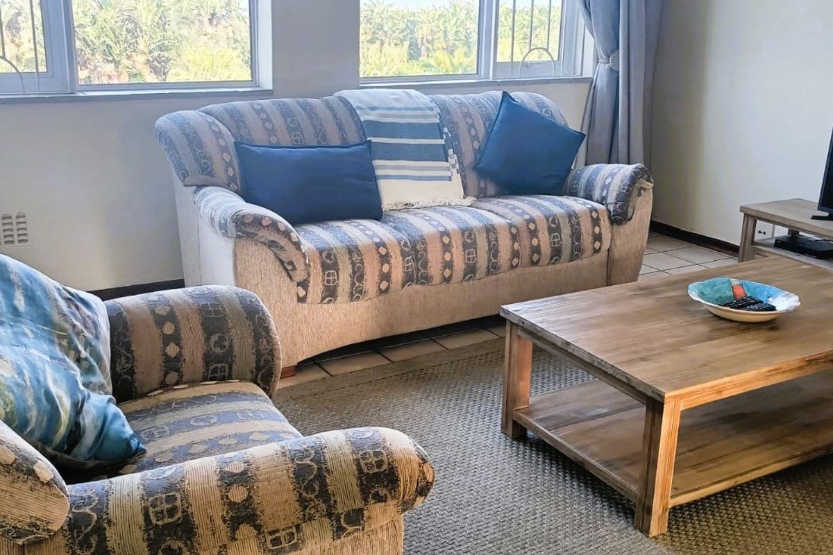 A bright living room featuring tiled flooring and large windows that provide ample natural light and exterior views.