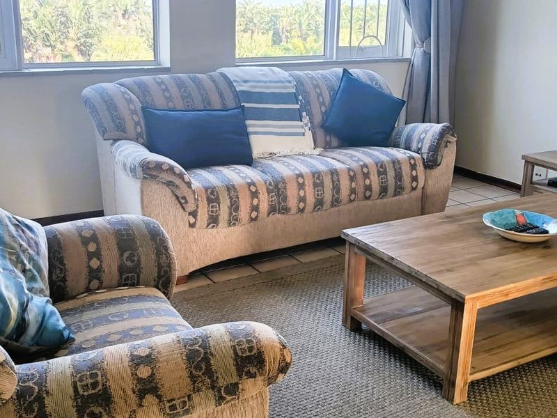 A bright living room featuring tiled flooring and large windows that provide ample natural light and exterior views.