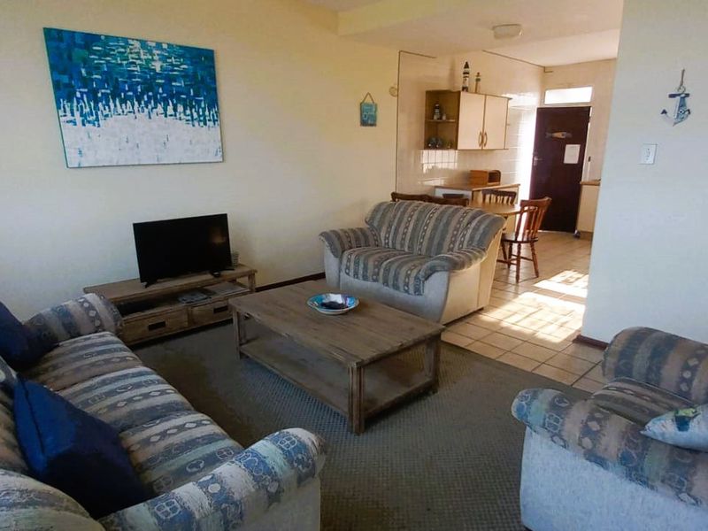 Open plan living area featuring a combined lounge and kitchen space with tiled and carpeted flooring, leading to an adjacent bathroom.