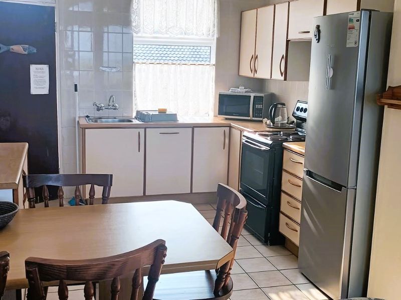 A functional kitchen featuring tiled flooring, built-in cabinetry, a tiled backsplash, and a stainless steel sink, offering a practical layout for daily use.