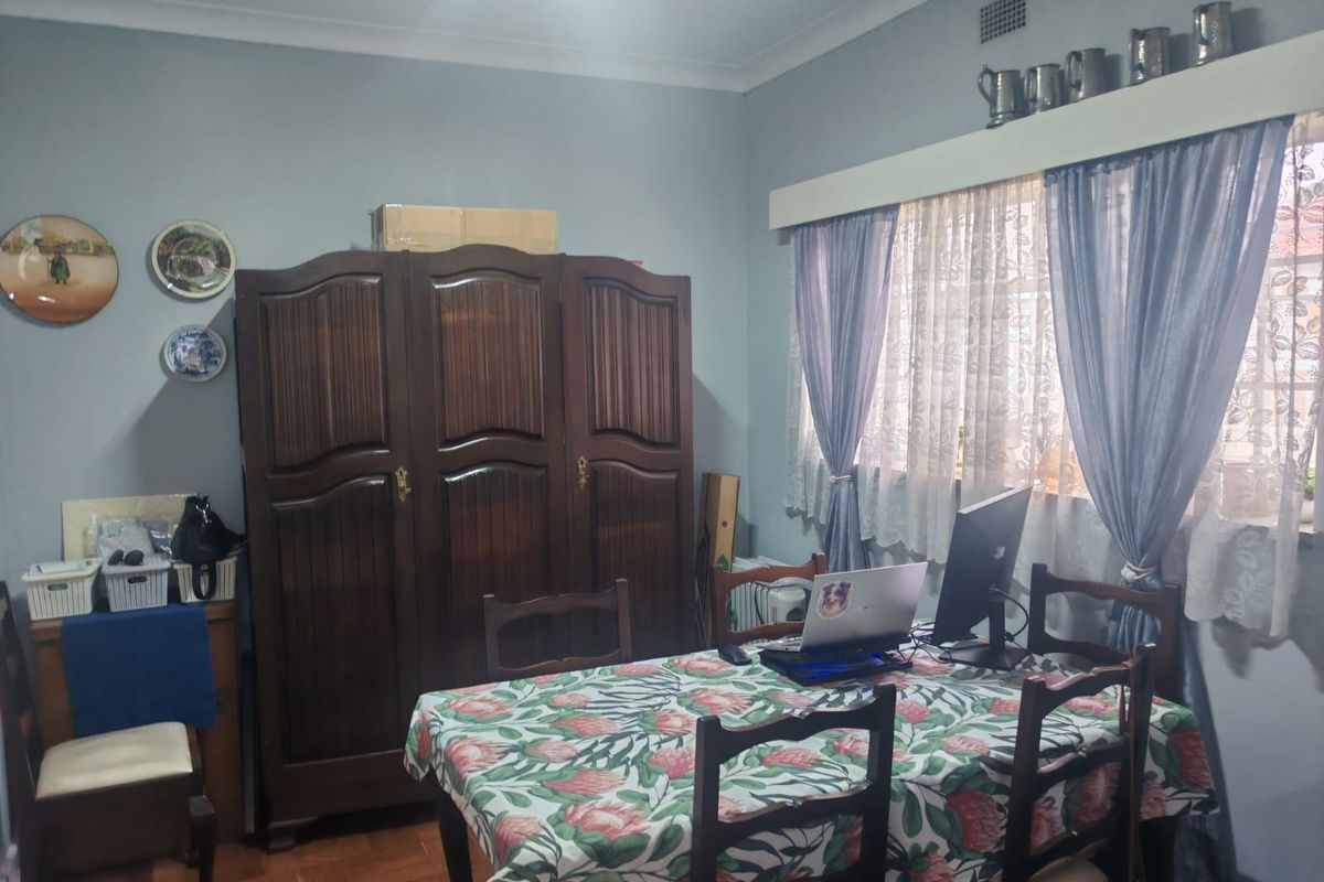 A bedroom featuring classic parquet flooring, coved ceilings, and a ventilation grille, offering a functional space with traditional architectural details.