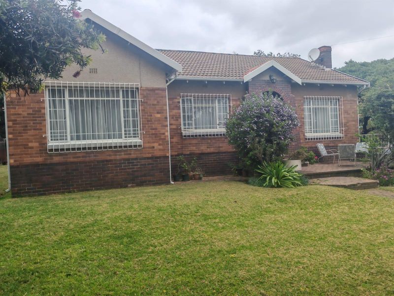 A traditional single-story brick house featuring a tiled roof, security bars on windows, and a front garden with a paved patio area.