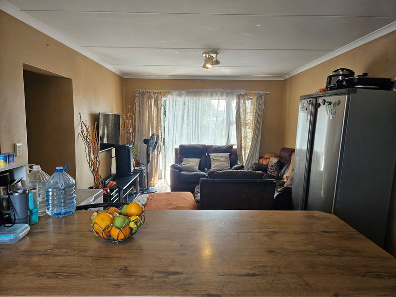 Open-plan living area featuring a breakfast bar, neutral wall tones, and direct access to a patio through sliding glass doors.