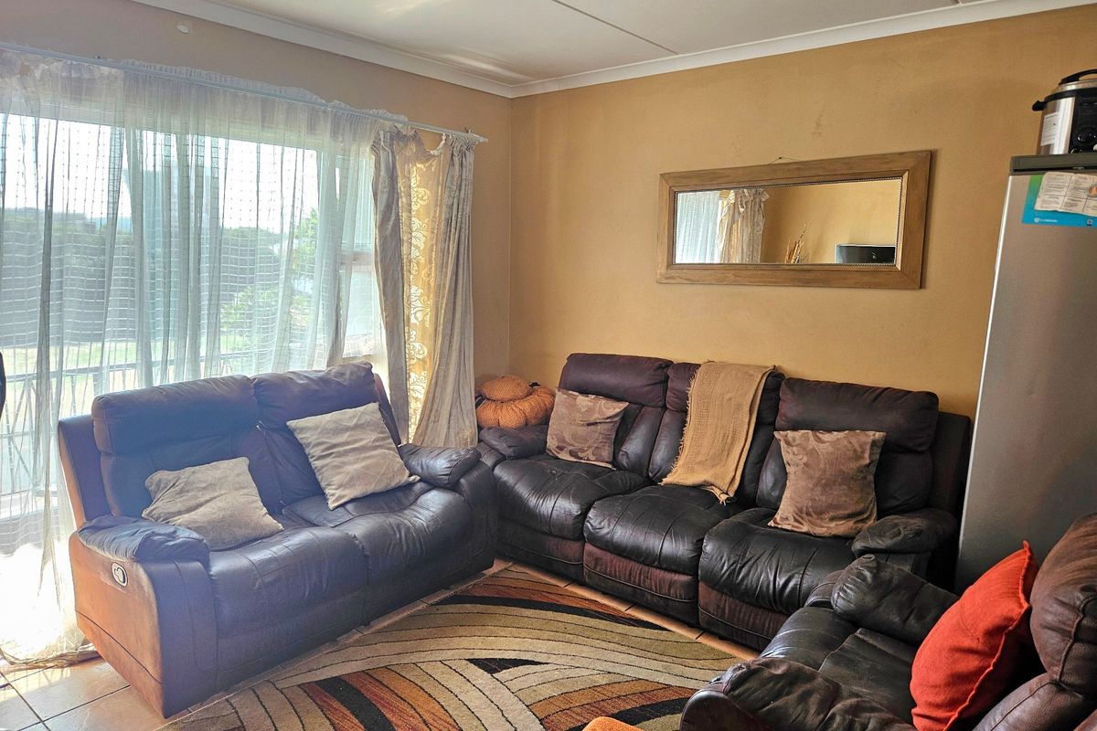 A comfortable living room featuring tiled flooring and a large sliding glass door that provides natural light and access to the exterior.