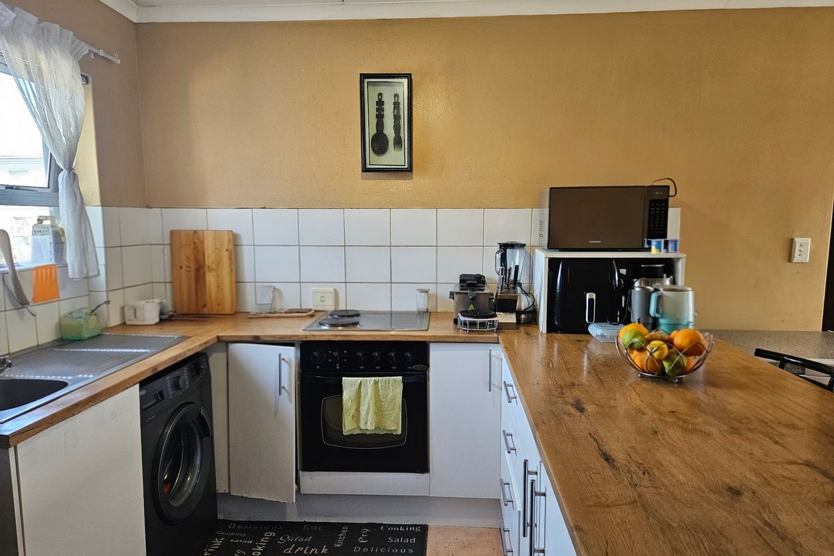 A functional kitchen featuring built-in cabinetry, a hob, an oven, and a tiled backsplash with laminate countertops.
