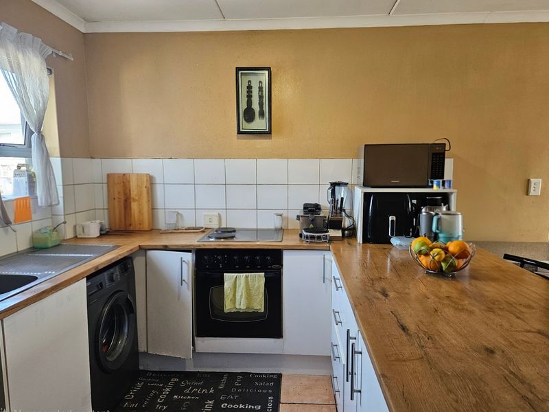 A functional kitchen featuring built-in cabinetry, a hob, an oven, and a tiled backsplash with laminate countertops.