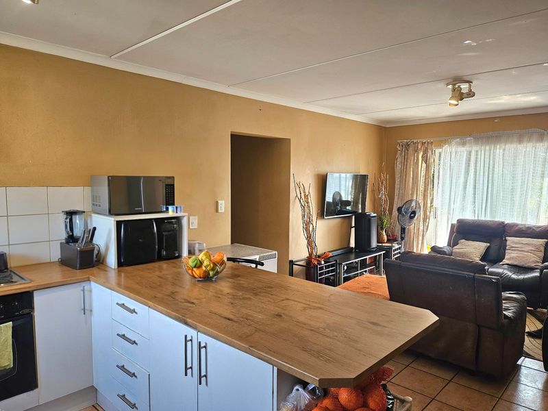 Open-plan living area featuring a kitchen with wooden countertops and built-in cabinetry, flowing into a lounge space with access to a patio.