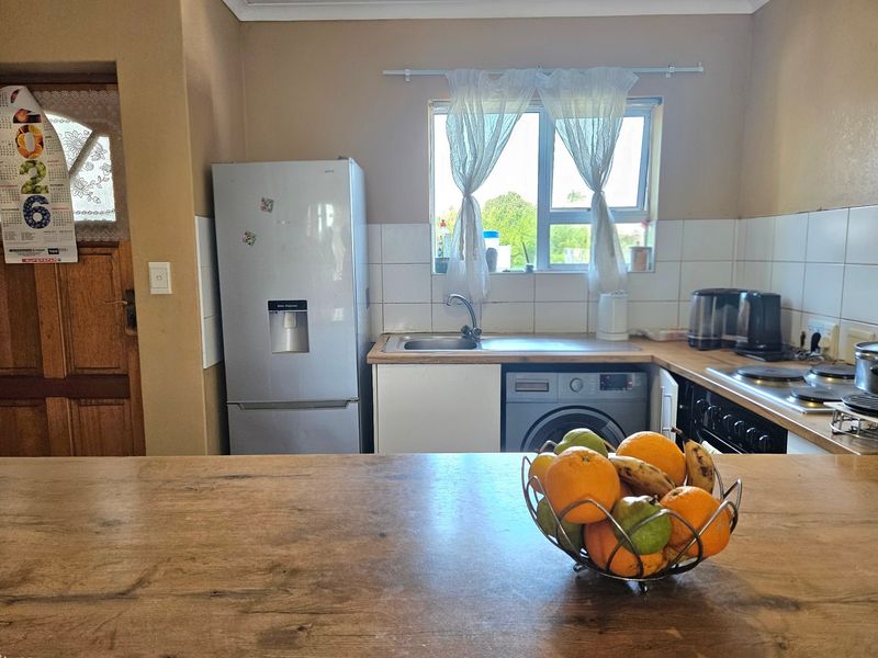 A functional kitchen featuring a tiled backsplash, laminate countertops, built-in oven, hob, and integrated space for laundry appliances.