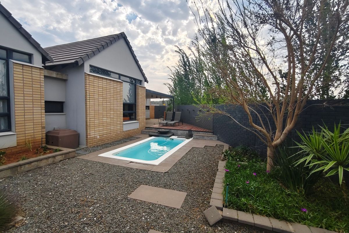 Rear exterior view of a townhouse featuring a plunge pool, timber decking, and a landscaped garden with brick boundary walls.